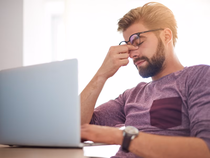 Business owner reviewing a website design on a laptop and pinching the bridge of their nose