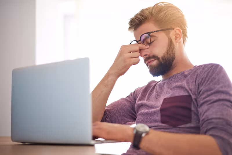 Business owner reviewing a website design on a laptop and pinching the bridge of their nose