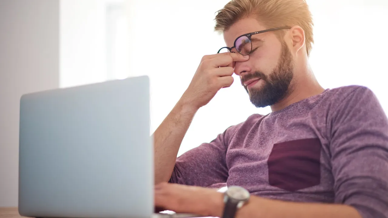 Business owner reviewing a website design on a laptop and pinching the bridge of their nose